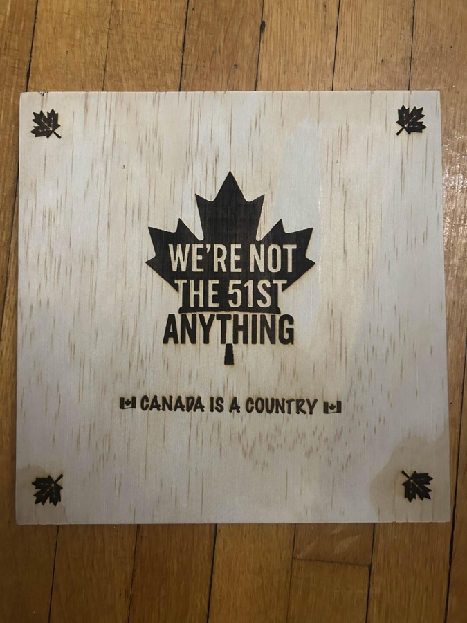 Engraved maple leaf board reading We're not the 51st anything — Canada is a country