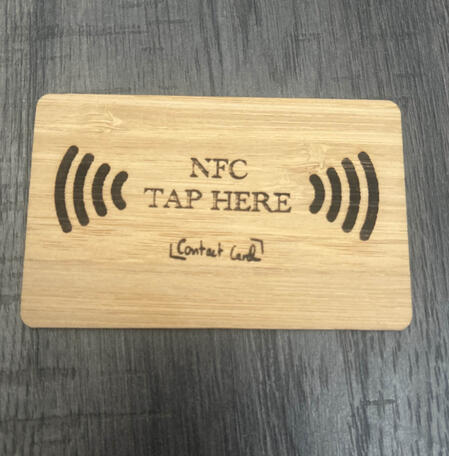 Close-up of a bamboo NFC card engraved with NFC Tap Here
